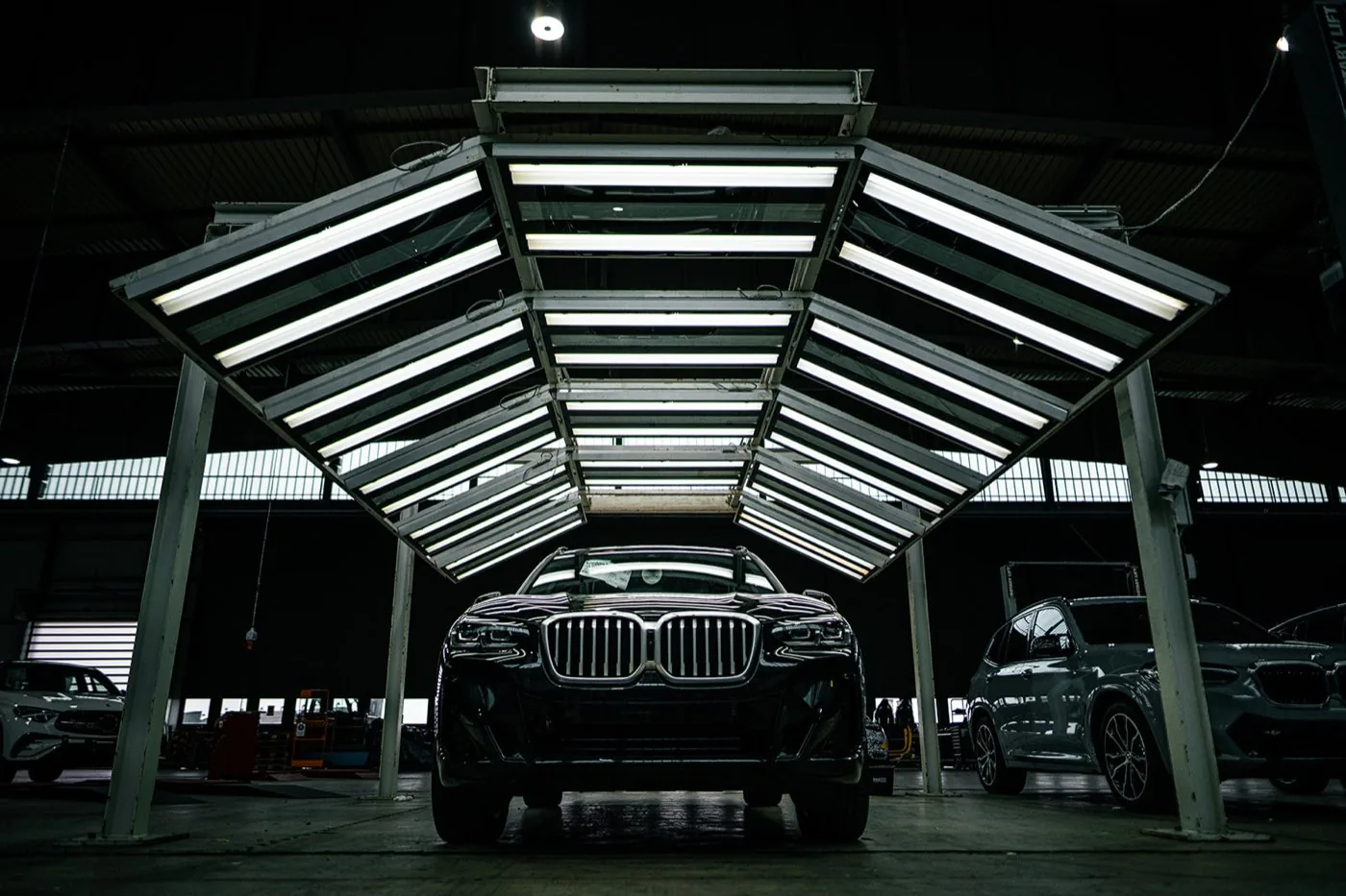 Unternehmensfotografie für Formel D: dunkler SUV frontal unter einem aufgeklappten Lichtdach mit Leuchtstoffröhren in einer Werkhalle